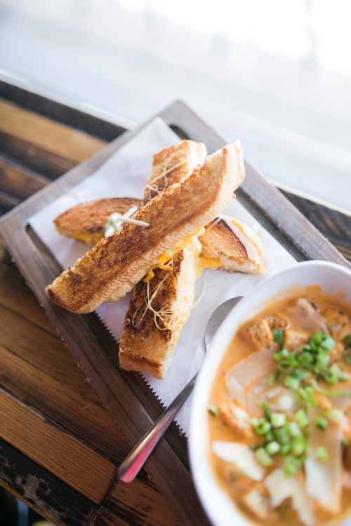 Toasted bread slices with melted cheese, served alongside a bowl of creamy soup topped with green onions.