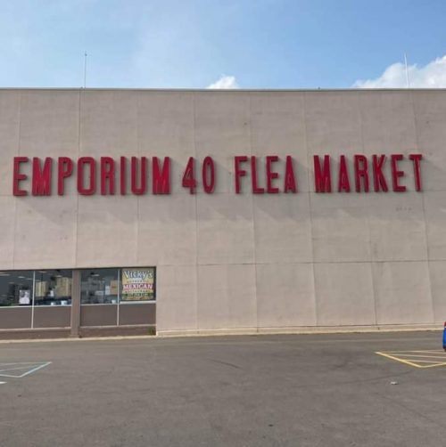Sign for "Emporium 40 Flea Market" on a building exterior, with a clear blue sky above.