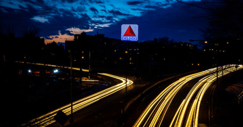 A cityscape at dusk with light trails from traffic and a glowing CITGO sign in the background.