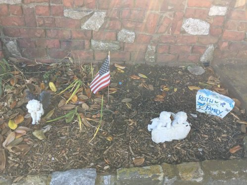 A small garden area with a U.S. flag, a lion statue, and a stone plaque reading "Keith & Family."