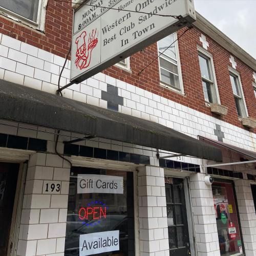 Sign for a sandwich shop featuring "Best Club Sandwich in Town" and "Gift Cards Available," with a neon "OPEN" display.