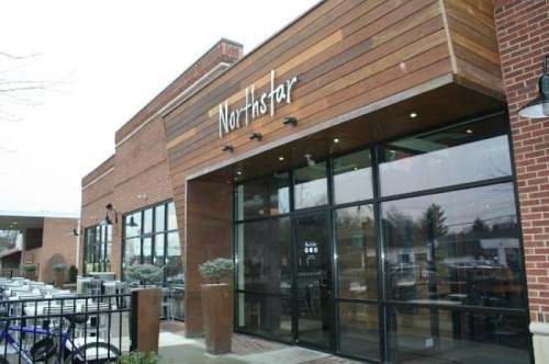 Exterior view of Northstar restaurant, featuring a wooden facade and large glass windows, with outdoor seating visible.
