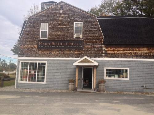 Exterior of Maine Distilleries building, featuring a rustic wooden facade and large windows.