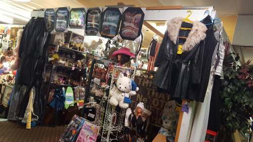 A colorful display of vintage items, clothing, and plush toys in a bustling thrift store.