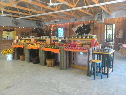A rustic market stall with baskets of apples, jars of preserves, and sunflowers, set in a warmly lit wooden space.