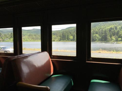 View from a train window showing a serene lake surrounded by green hills and trees.