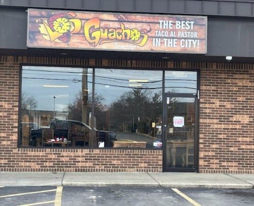 Exterior of Guachinango Taqueria, featuring a sign that reads "The Best Taco Al Pastor in the City!" on a brick building.