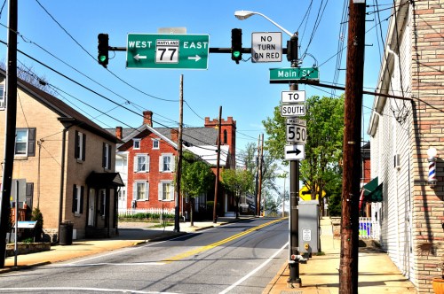 Street view featuring traffic lights, road signs for Maryland routes, and a quiet neighborhood with houses.