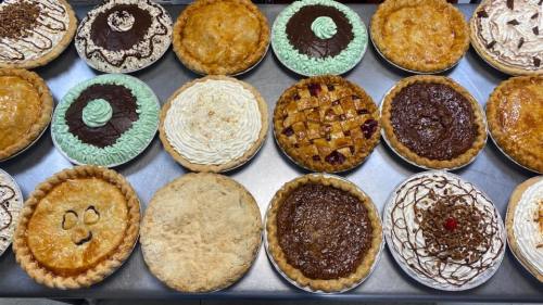 A variety of delicious pies arranged on a table, featuring different flavors and toppings.