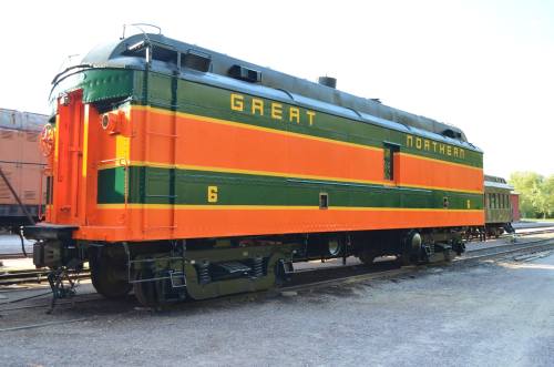 A vintage Great Northern locomotive in orange and green, parked on a railway track.