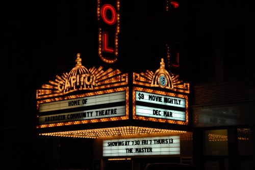 A vintage theater marquee lit up at night, advertising "$9 Movie Nightly" and showing "The Master."