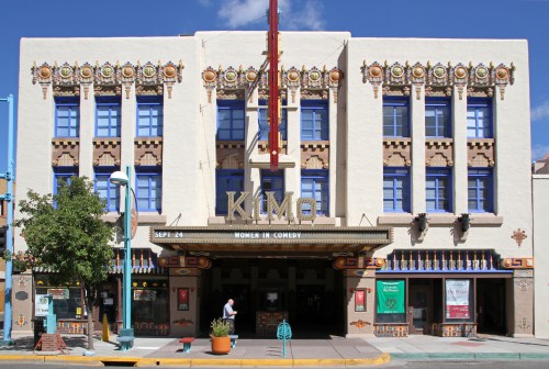 Historic Kimo Theatre with colorful Art Deco design, featuring a marquee and decorative elements, under a blue sky.