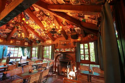 Cozy interior of a rustic restaurant with wooden beams, tables, and a fireplace, adorned with vintage posters.