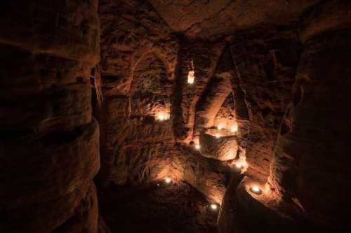 Dimly lit cave interior with stone walls and candles illuminating the space.