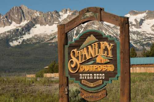 Sign for Stanley Outpost River Beds, with mountains in the background and clear blue skies.