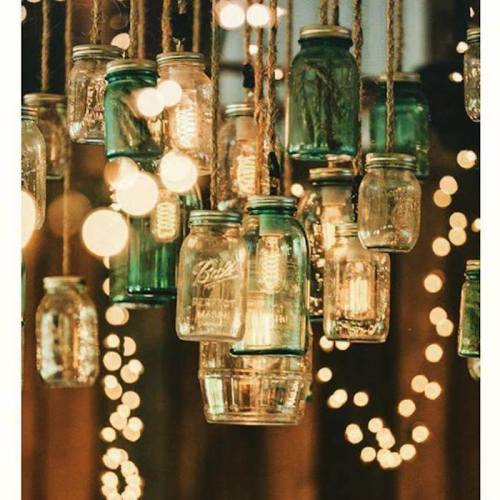 Hanging glass jars with lights, surrounded by soft bokeh, create a warm, inviting atmosphere.