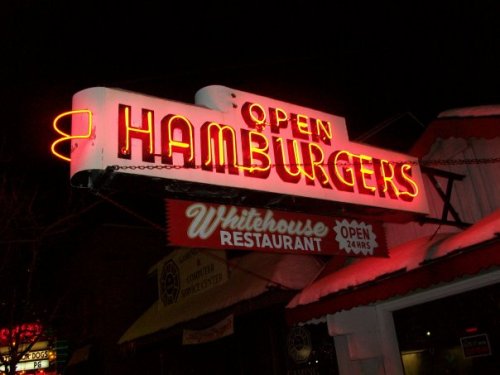 Neon sign reading "Open Hamburgers" at Whitehouse Restaurant, illuminated at night.