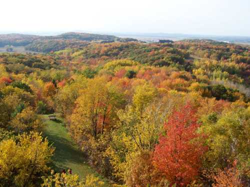 A scenic view of rolling hills covered in vibrant autumn foliage, showcasing shades of red, orange, and yellow.