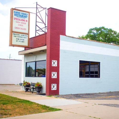 Exterior of Karas Family Restaurant, featuring a sign and a bench outside, highlighting its specialty in Mediterranean cuisine.