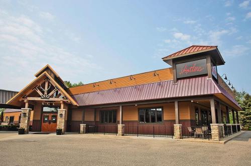Exterior view of a restaurant with a wooden facade, peaked roof, and a sign reading "Antlers." Clear blue sky above.