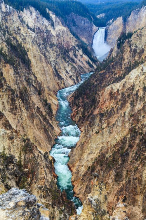 A stunning view of a winding river through a rugged canyon, with a waterfall cascading in the distance.