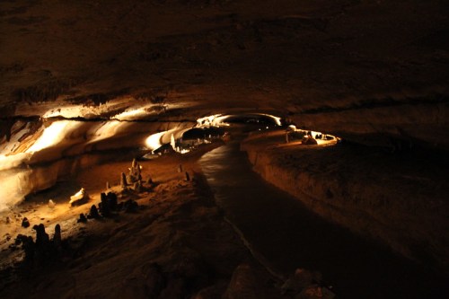 A dimly lit cave interior with a winding path and rock formations illuminated by soft lights.