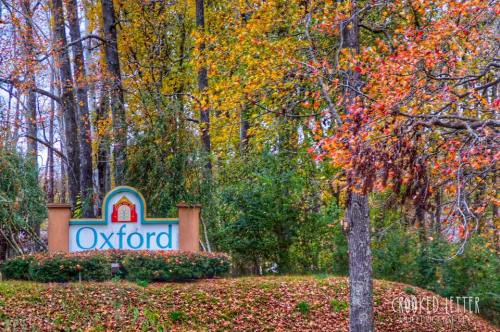 A colorful autumn scene featuring a sign that reads "Oxford" surrounded by trees with vibrant fall foliage.