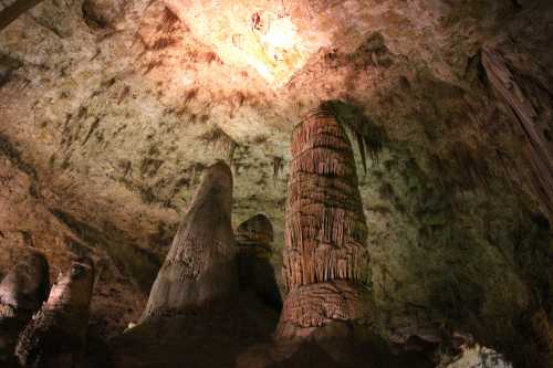 Stalactites and stalagmites in a dimly lit cave, showcasing unique rock formations and textures on the ceiling and ground.