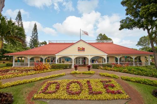 A colorful Dole plantation building surrounded by lush greenery and a flowerbed spelling "DOLE."