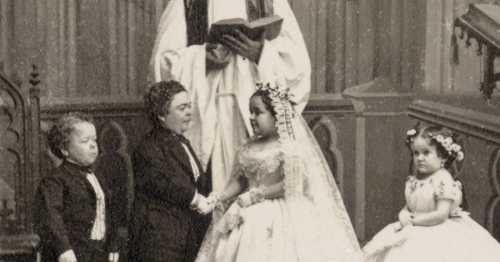 A historic black-and-white photo of a wedding ceremony with four individuals, including a bride and groom, in formal attire.