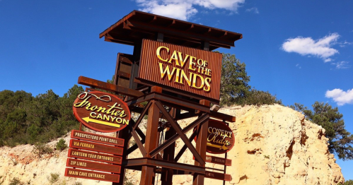 Sign for "Cave of the Winds" with directional information for attractions like zip lines and dining options.