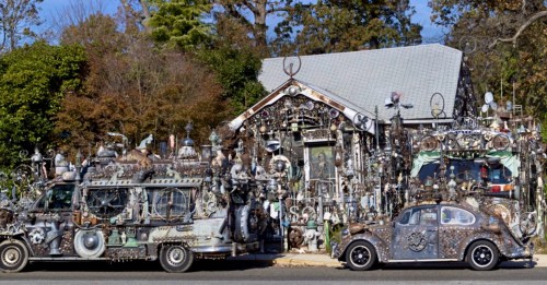 A quirky house and two decorated cars covered in various metal sculptures and artistic installations.