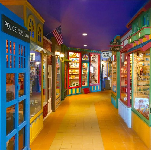 Colorful indoor shopping area with whimsical storefronts and displays, featuring a police box and various collectibles.