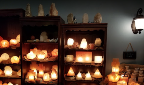 Shelves filled with various salt lamps and crystals, glowing softly in a cozy, warmly lit space.