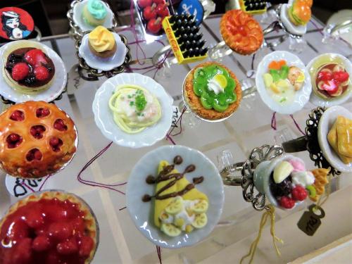 A display of colorful miniature food-themed rings, featuring desserts and dishes on small plates.