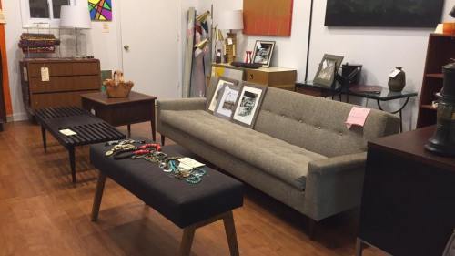 A cozy interior featuring a gray sofa, coffee table, framed photos, and various decorative items in a stylish setting.