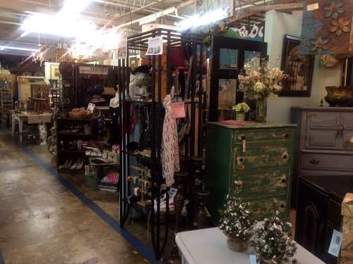 A vintage shop aisle filled with various home decor items, furniture, and decorative accessories.