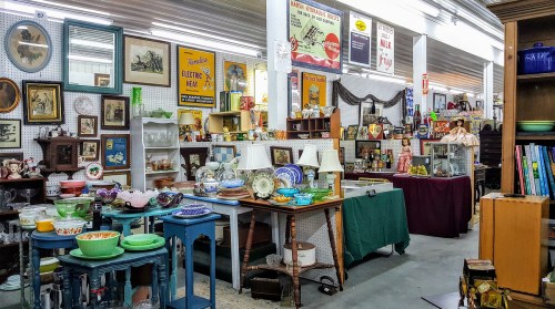 A vintage shop filled with various antiques, including dishes, furniture, and decorative items on display.