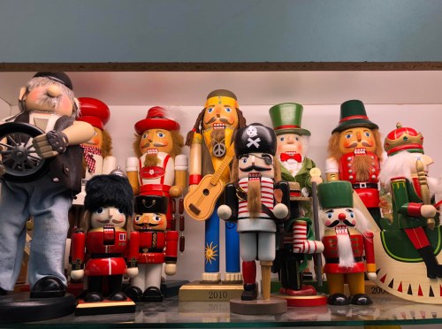 A collection of colorful nutcracker figurines in various costumes, displayed on a shelf.