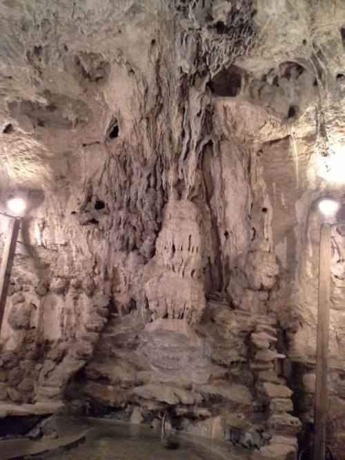 A rocky cave interior with stalactites and stalagmites, illuminated by soft lights.