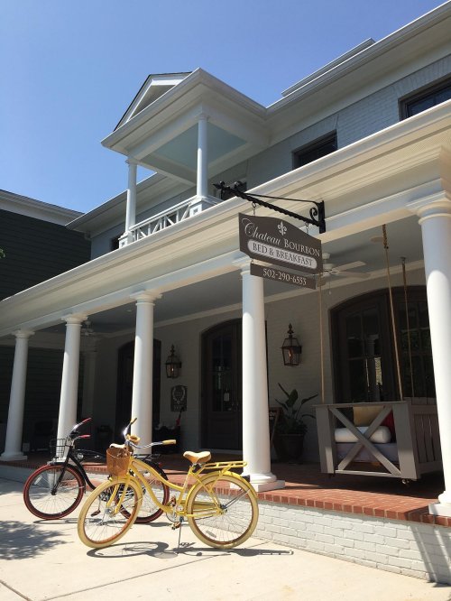 A charming bed and breakfast with a sign, featuring two bicycles parked in front on a sunny day.