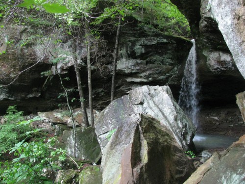 A serene waterfall cascades over rocks in a lush, green forest setting.