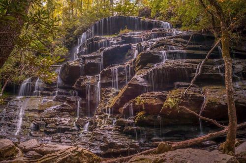 A serene waterfall cascading over rocky cliffs, surrounded by lush greenery and trees.