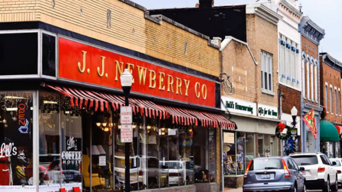 A street view of a small town featuring J.J. Newberry Co. and other shops, decorated for the holiday season.