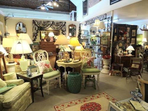 A cozy vintage shop filled with various lamps, furniture, and decor items, creating a warm and inviting atmosphere.