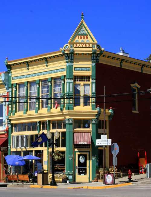 Colorful historic building with ornate details, featuring large windows and a decorative roof, set against a clear blue sky.