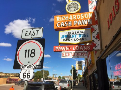 Signage for Richardson Cash Pawn and US Route 66 in New Mexico, featuring colorful advertisements and a clear blue sky.