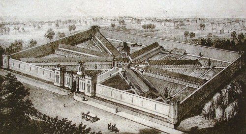 Aerial view of a historic prison with a star-shaped layout, surrounded by walls and greenery.