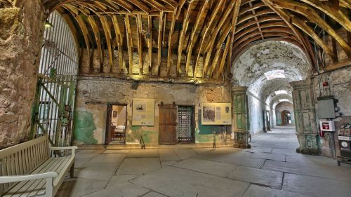 Interior of a historic building with stone walls, wooden beams, and doorways leading to other rooms.