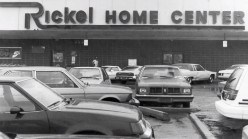 Black and white photo of Rickel Home Center with parked cars in front and people walking nearby.